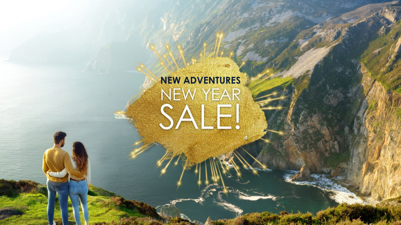 A couple stands on a cliff overlooking the ocean and mountains, with text overlay: 